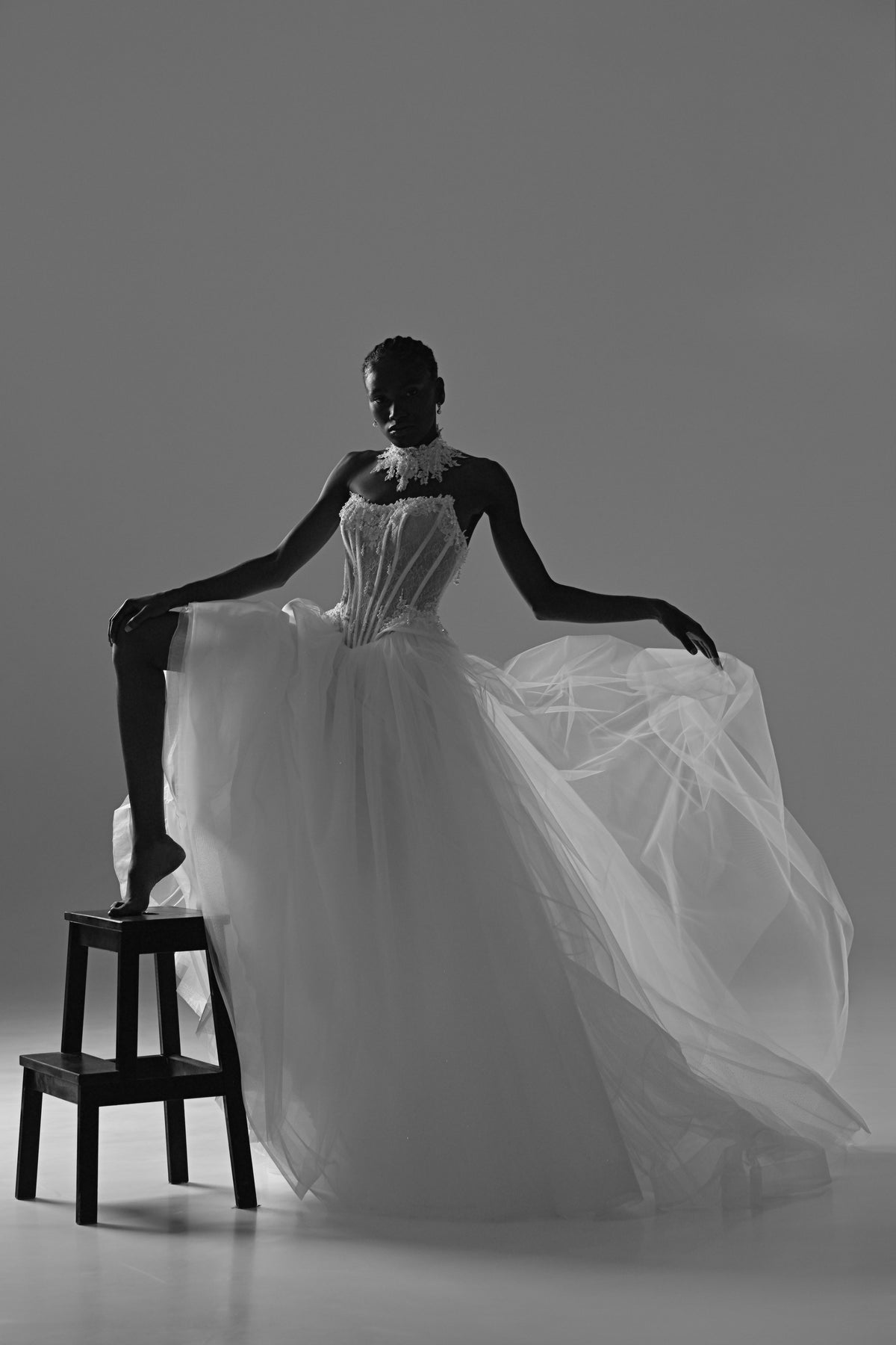 Tulle ball gown wedding dress – black and white pose on a stool with the tulle skirt