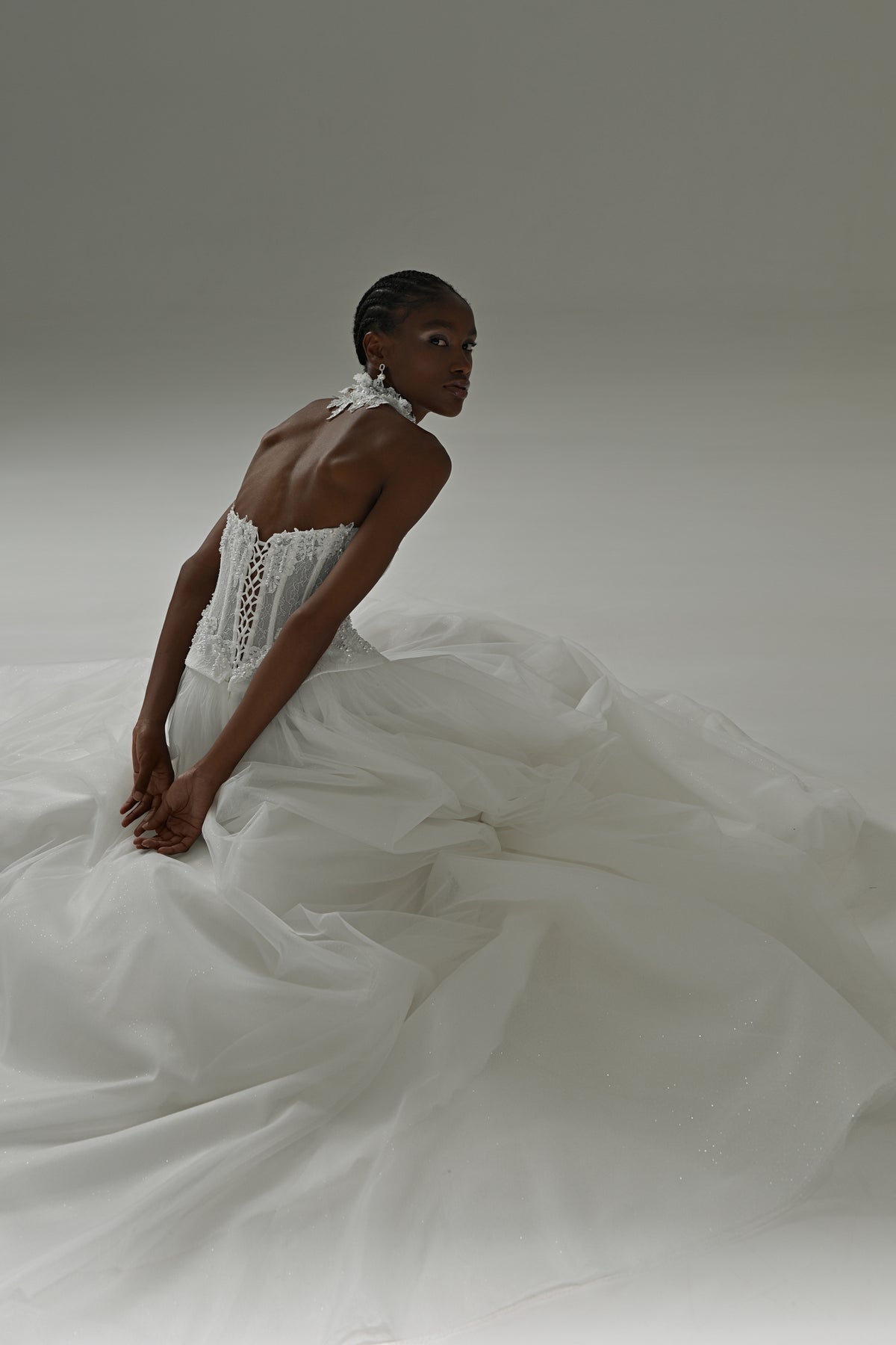 Tulle ball gown wedding dress – seated in the voluminous tulle skirt, side view of the corset back