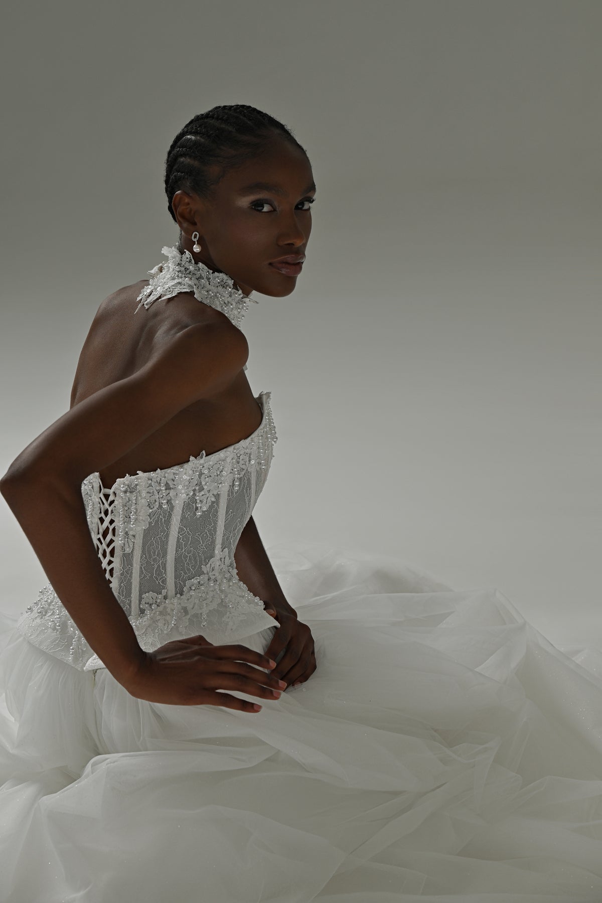 Tulle ball gown wedding dress with lace corset and choker – seated front view with hands at the waist