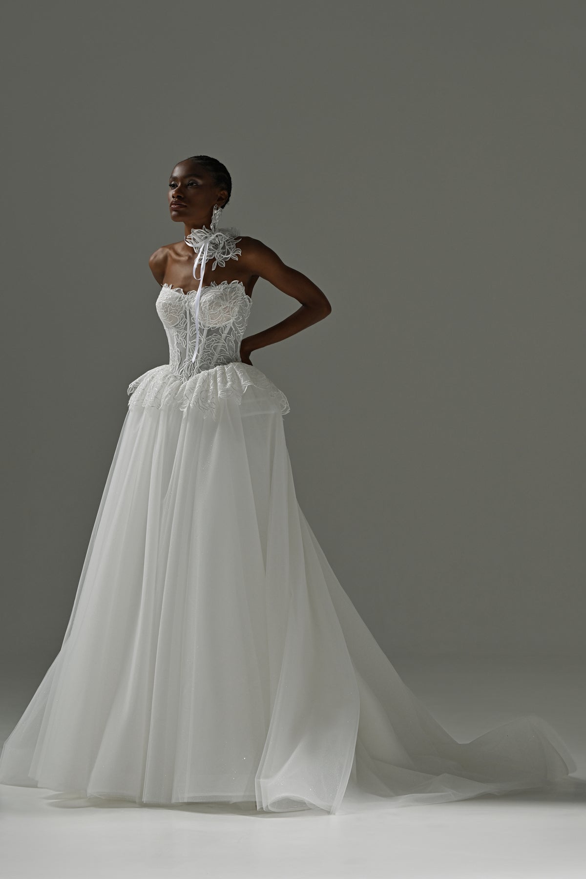 Strapless lace corset wedding dress with peplum waist and full tulle skirt – full-length front view, hands on hips
