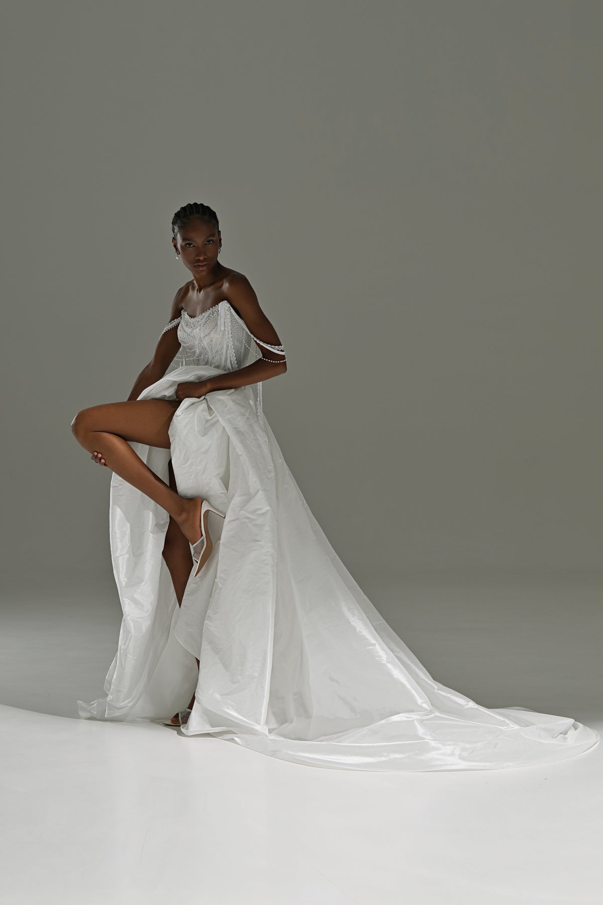 Taffeta wedding dress with high-slit overskirt – model posing with one leg raised, train behind