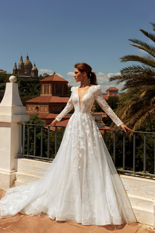 Bride in long sleeve lace A-line bridal gown with puffy shoulders, illusion deep-V back, button closure, and chapel train.