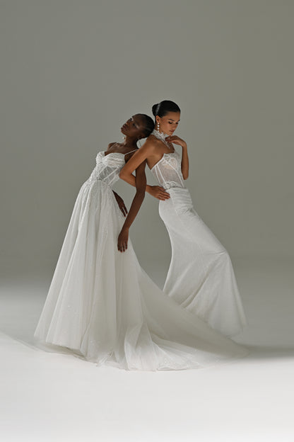 Lace sheath wedding dress with sheer cape – two brides embracing with the cape and train flowing