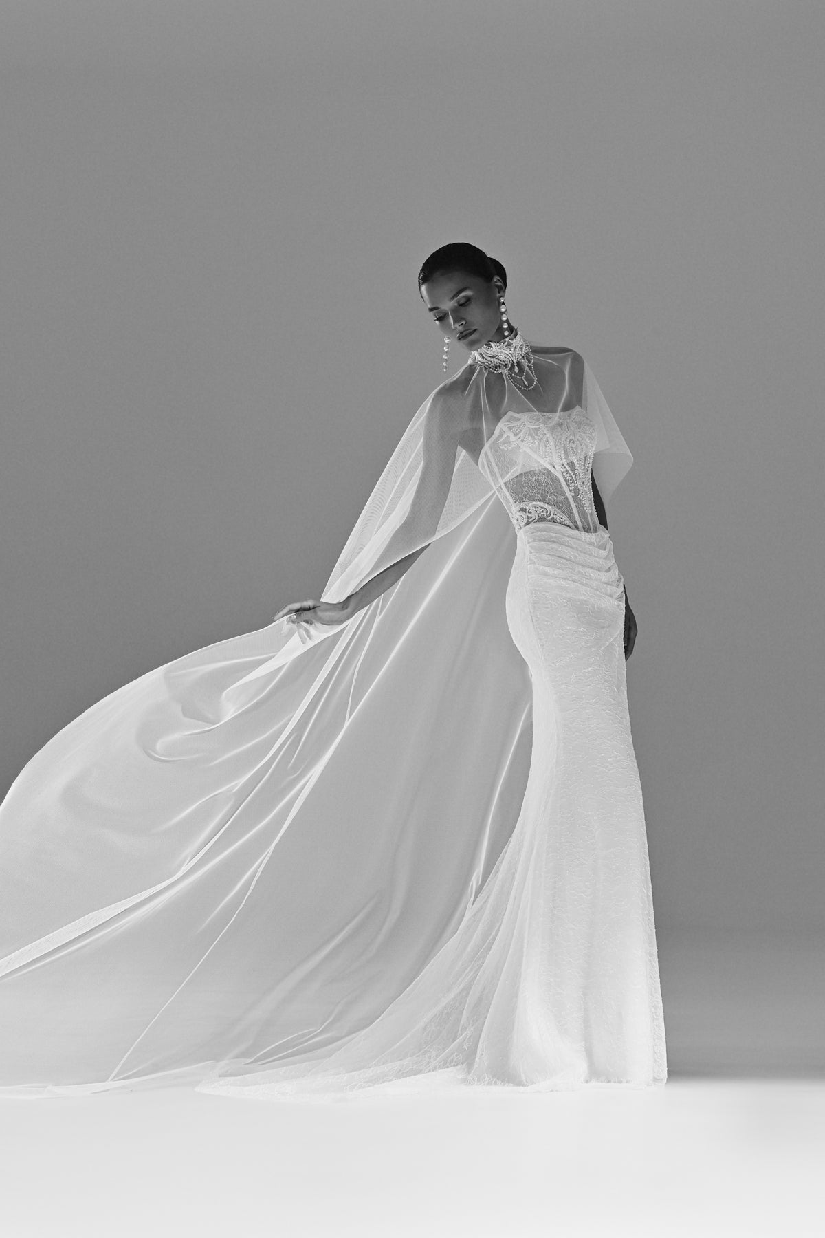 Lace sheath wedding dress with sheer cape – black and white view of the cape in motion