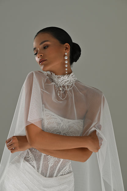 Lace sheath wedding dress – close-up of the high-neck sheer cape and corset bodice, arms crossed