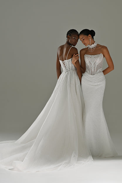 Lace sheath wedding dress with sheer cape – two brides standing together, full-length view