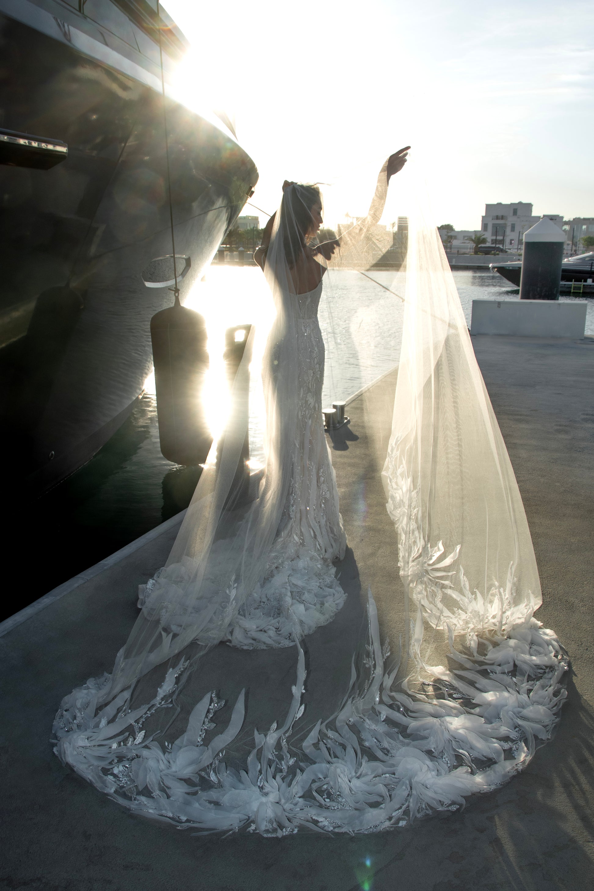 Beaded sheath wedding dress with illusion corset bodice and feather-textured tulle chapel train.