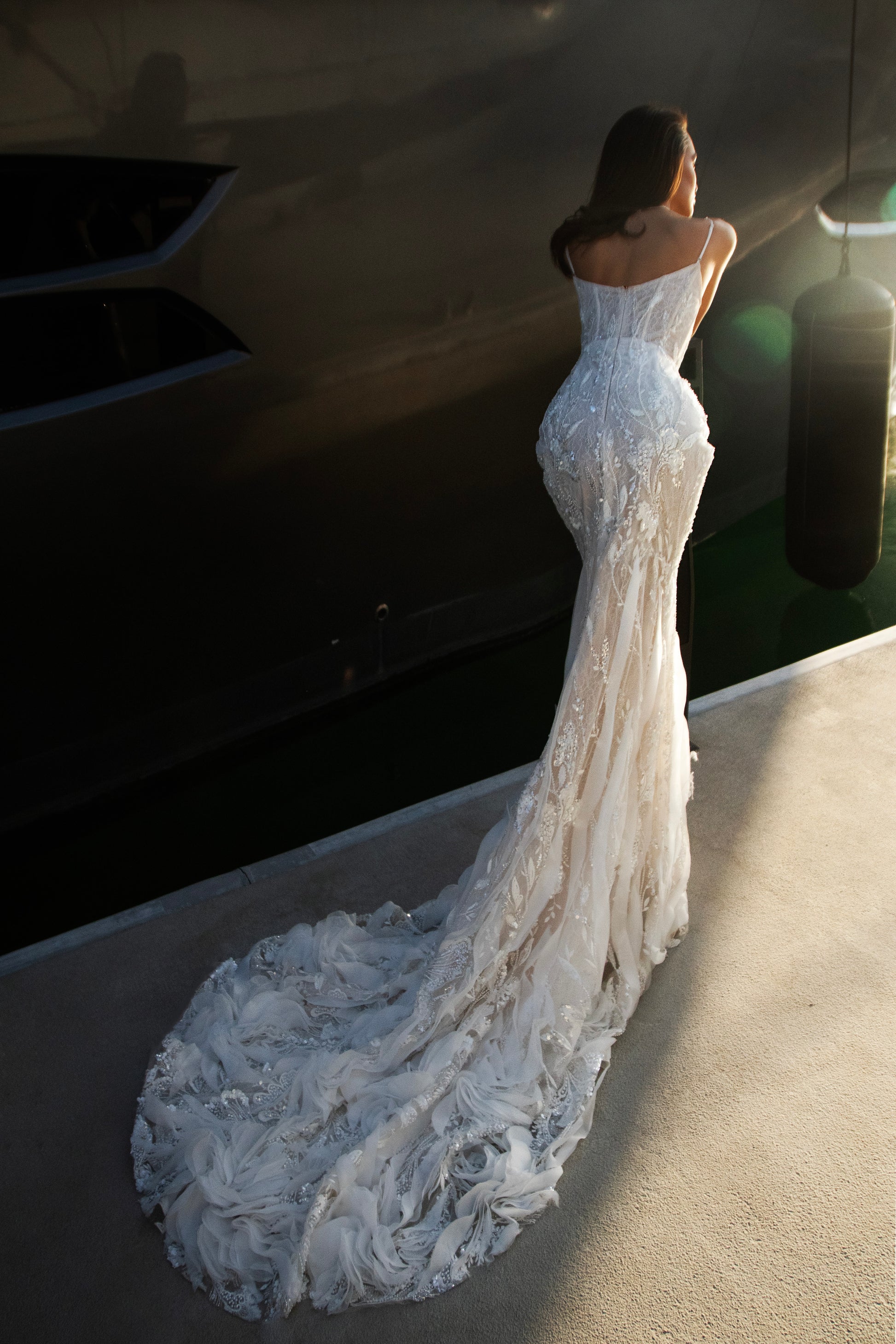 Beaded sheath wedding dress with illusion corset bodice and feather-textured tulle chapel train.