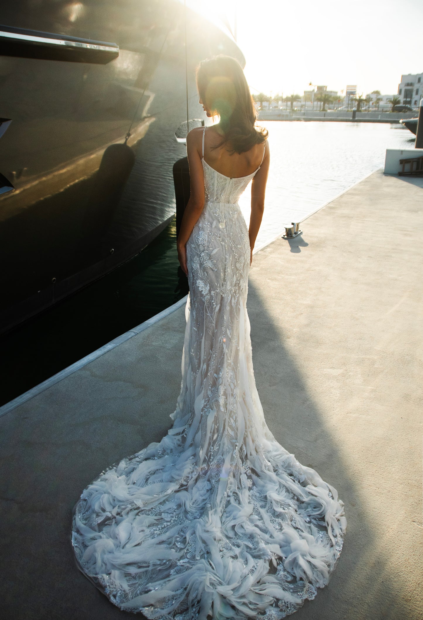 Beaded sheath wedding dress with illusion corset bodice and feather-textured tulle chapel train.