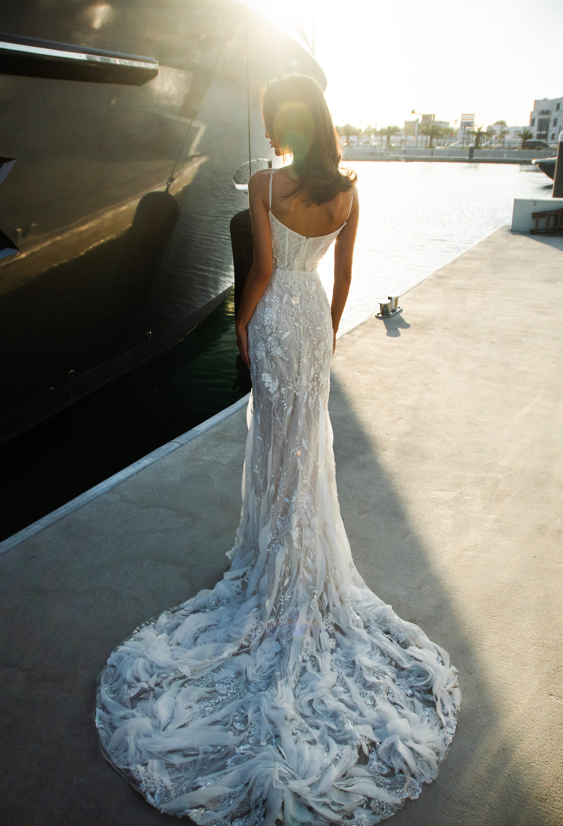 Beaded sheath wedding dress with illusion corset bodice and feather-textured tulle chapel train.