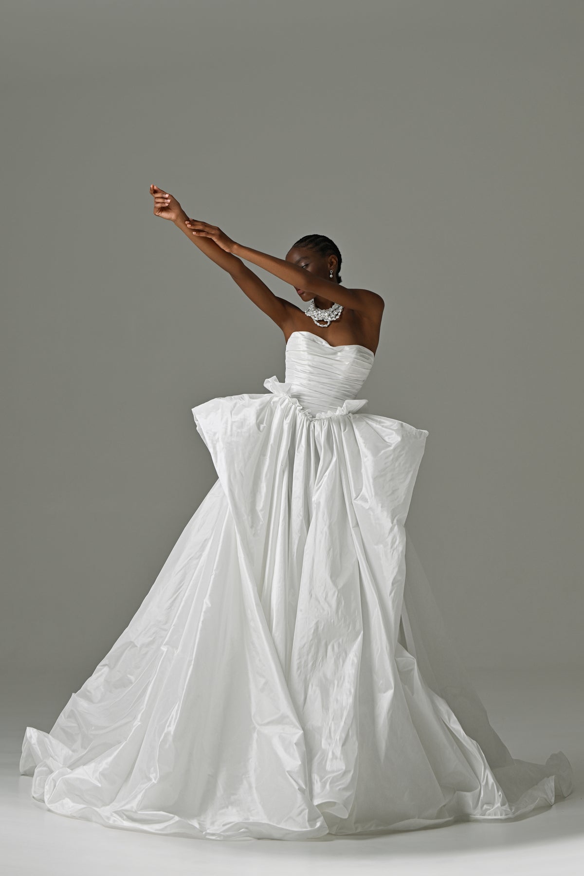 Strapless taffeta ball gown wedding dress with oversized bow – front view, one arm raised