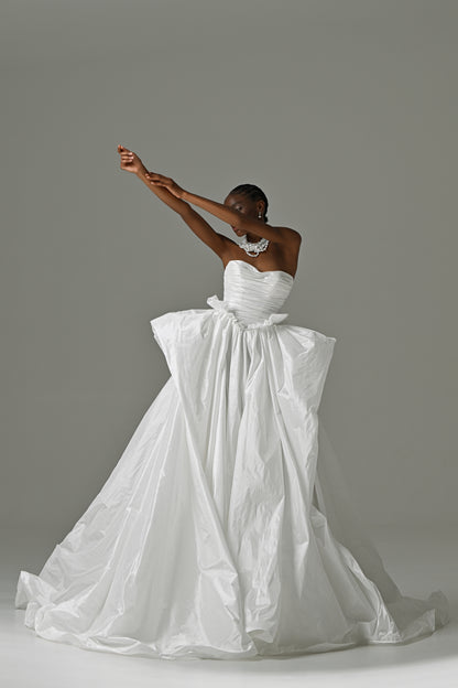 Strapless taffeta ball gown wedding dress with oversized bow – front view, one arm raised