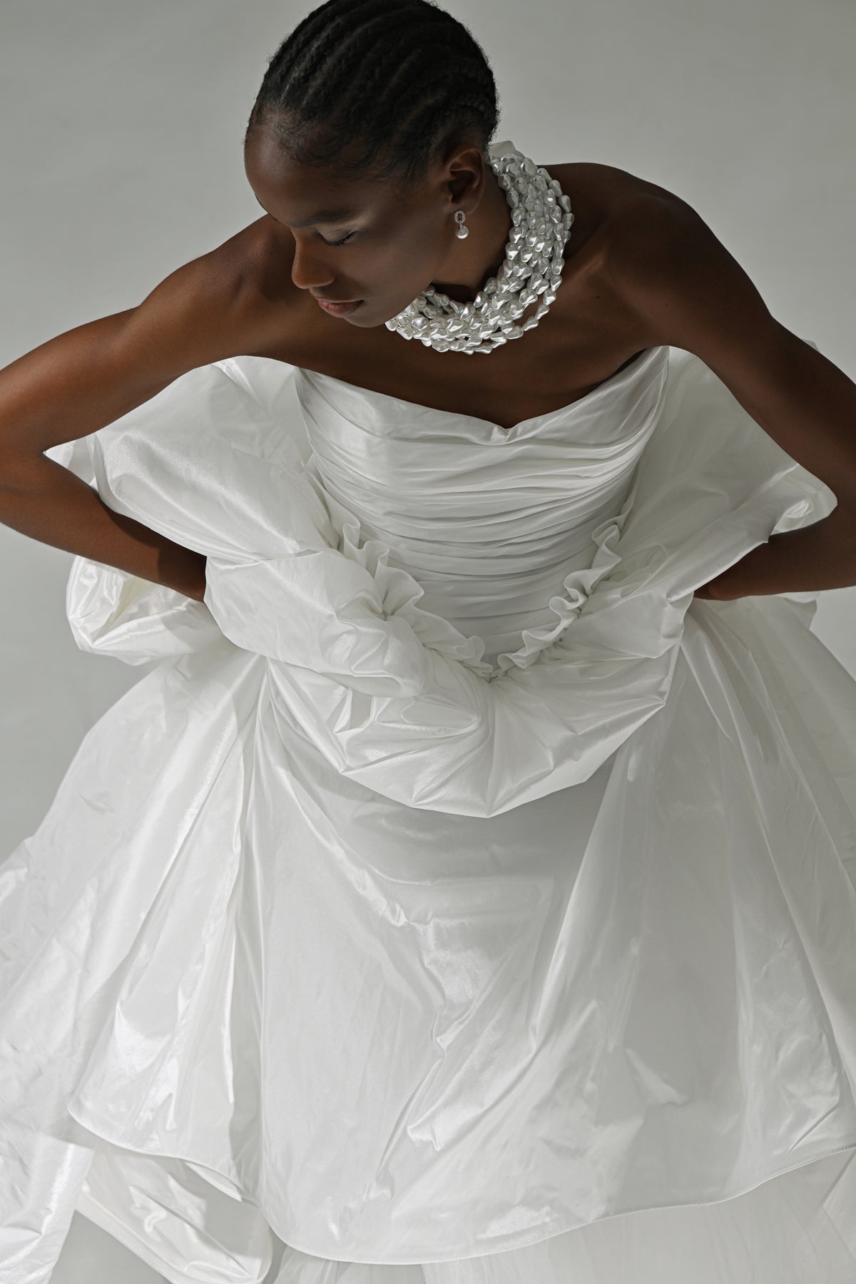 Strapless taffeta ball gown wedding dress – high-angle view of the bodice with hands on the skirt