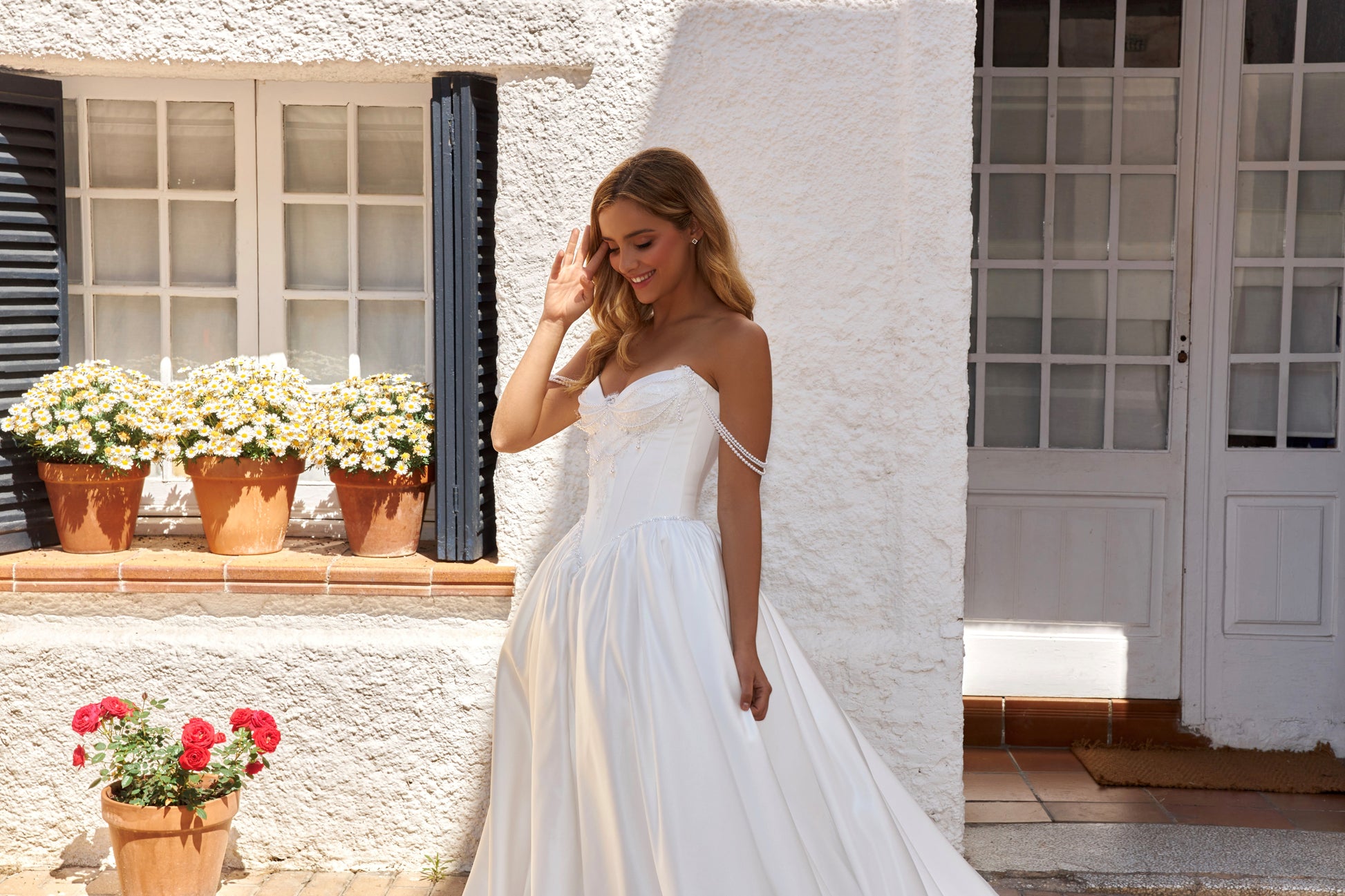 Bride wearing sleeveless satin A-line bridal gown with sweetheart neckline, pearl straps, drop-down waist, zip closure, open back, and chapel train.