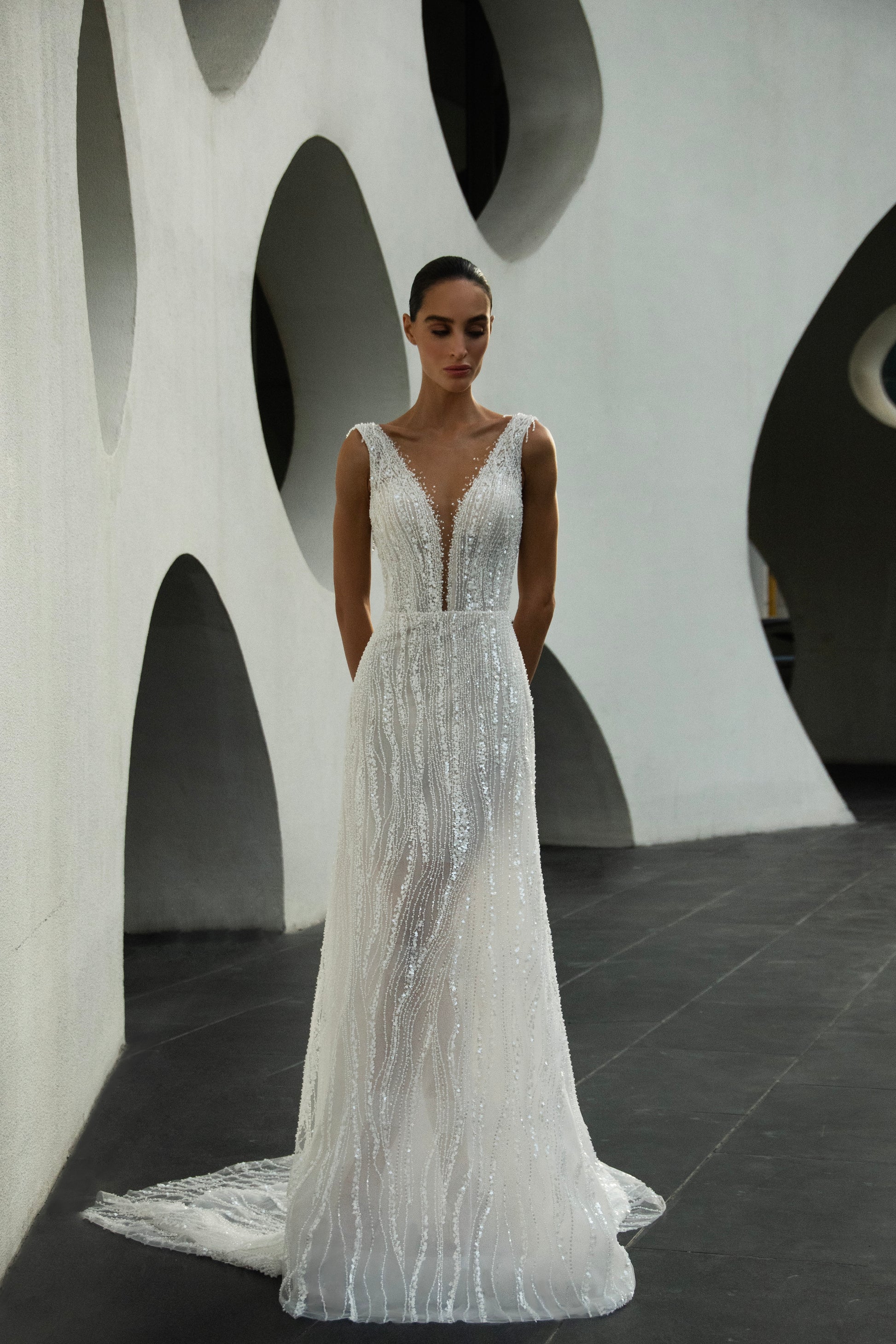 Radiant beaded A-line wedding gown with deep V neckline and open back, featuring a soft flowing tulle train.