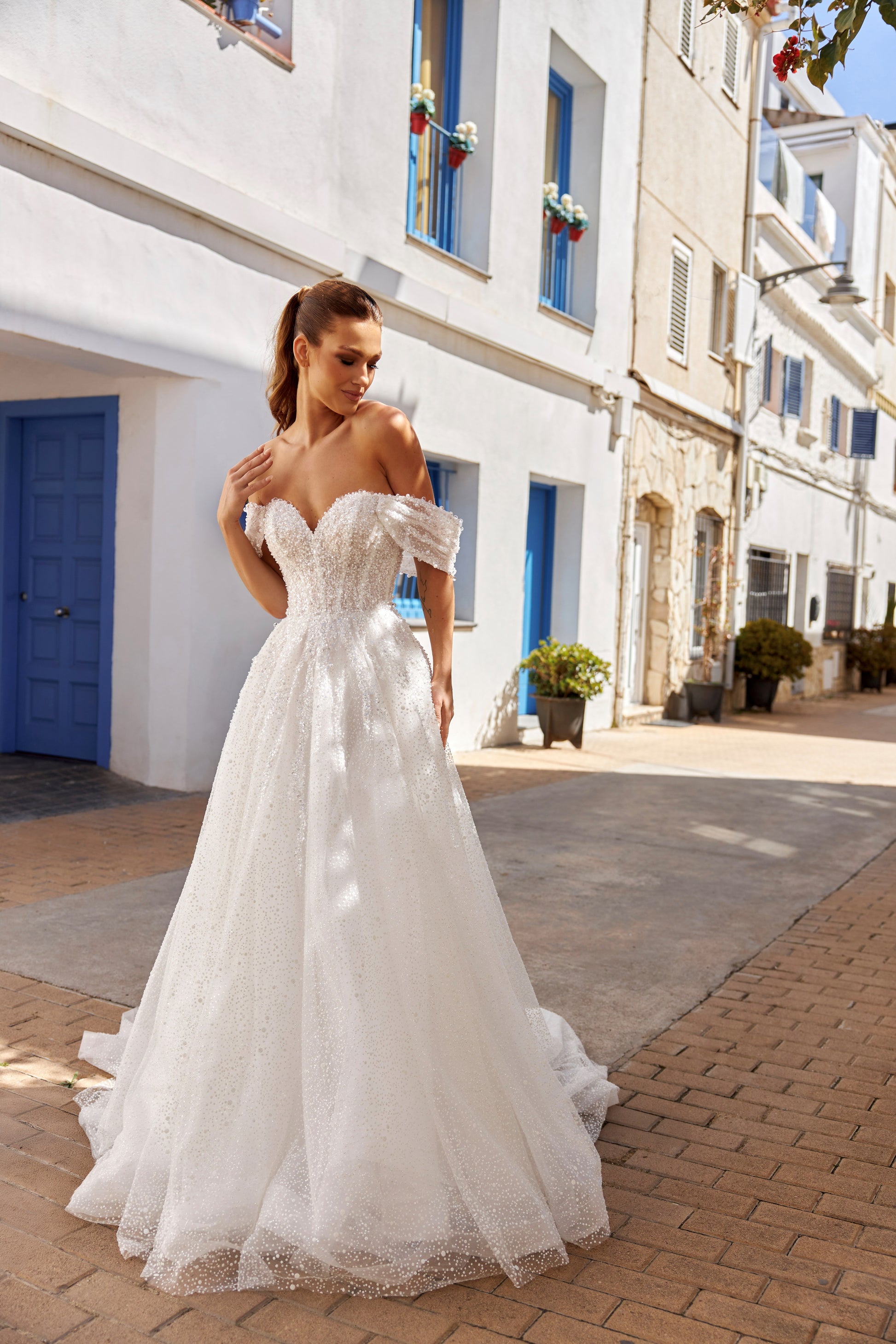 Sleeveless A-line lace bridal gown with sweetheart neckline, pearl straps, pearl and sequin embroidery, and glittering tulle skirt.
