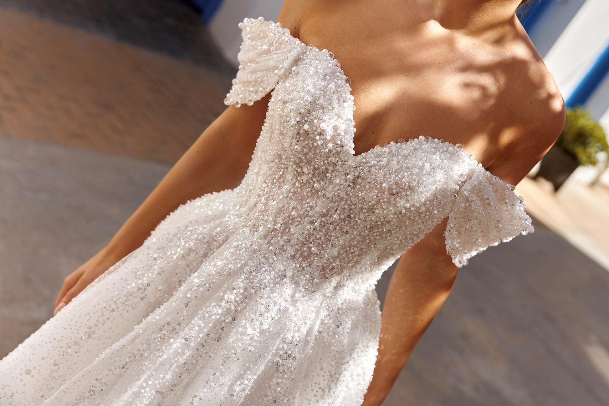 Sleeveless A-line lace bridal gown with sweetheart neckline, pearl straps, pearl and sequin embroidery, and glittering tulle skirt.