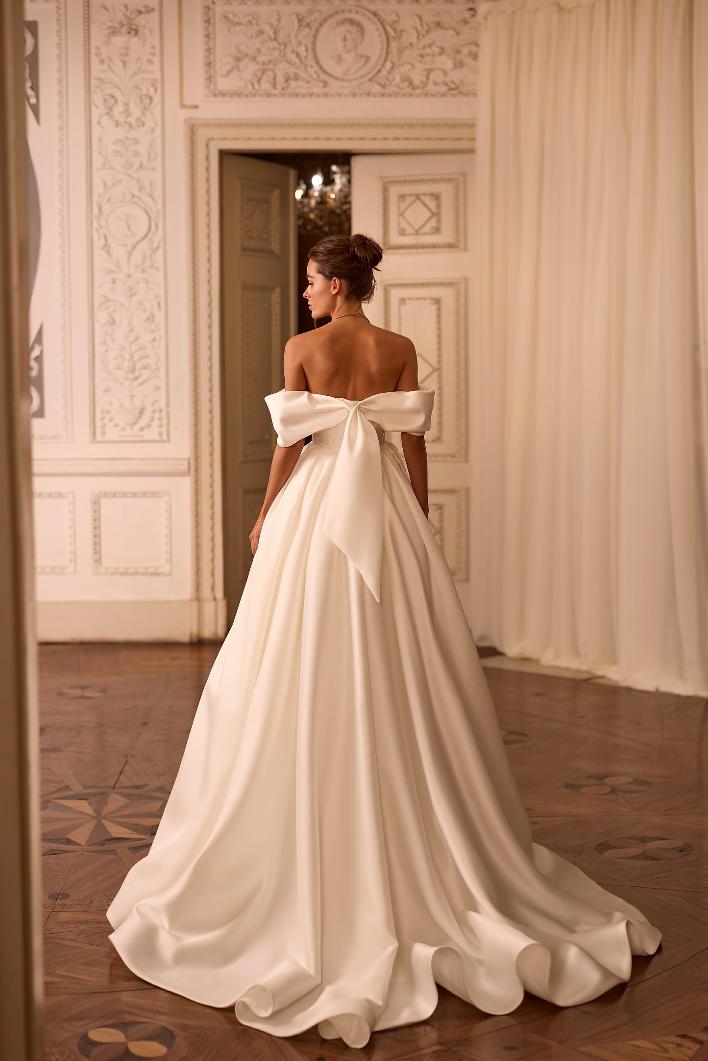 Bride wearing a two-in-one mini wedding dress with detachable mikado train and sculpted off-shoulder bodice.

