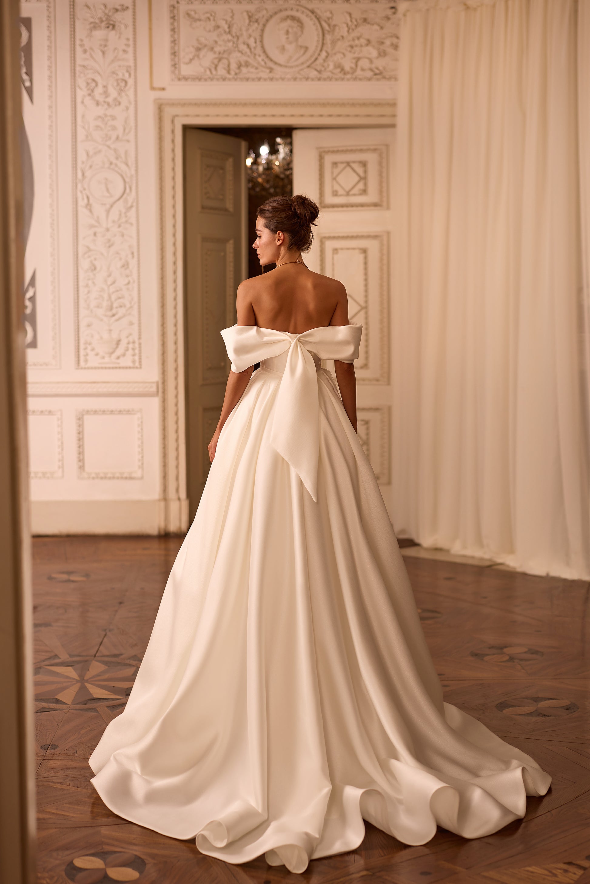 Bride wearing a two-in-one mini wedding dress with detachable mikado train and sculpted off-shoulder bodice.

