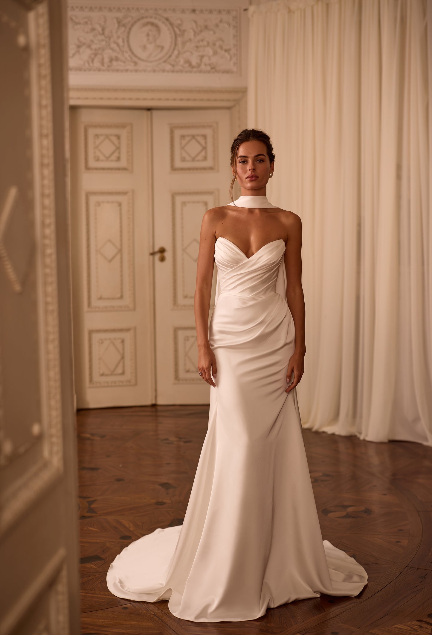 Modern bride wearing a minimalist satin sheath dress with draped V-neck, lace-up back, and scarf-style choker.

