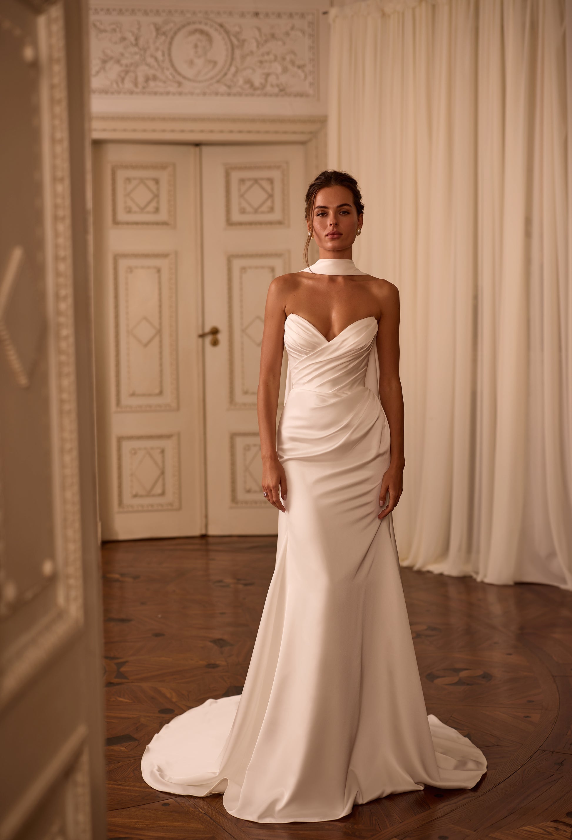Modern bride wearing a minimalist satin sheath dress with draped V-neck, lace-up back, and scarf-style choker.


