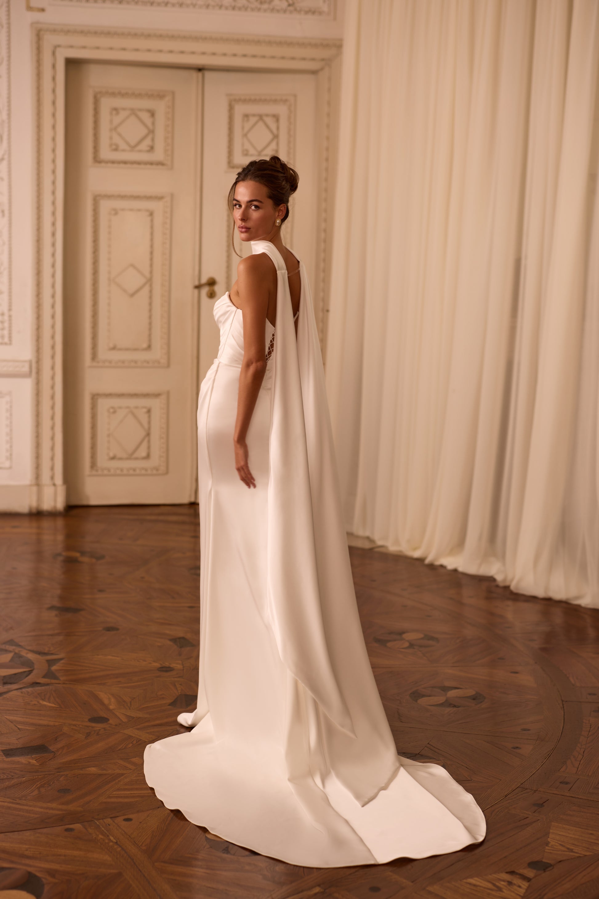 Modern bride wearing a minimalist satin sheath dress with draped V-neck, lace-up back, and scarf-style choker.

