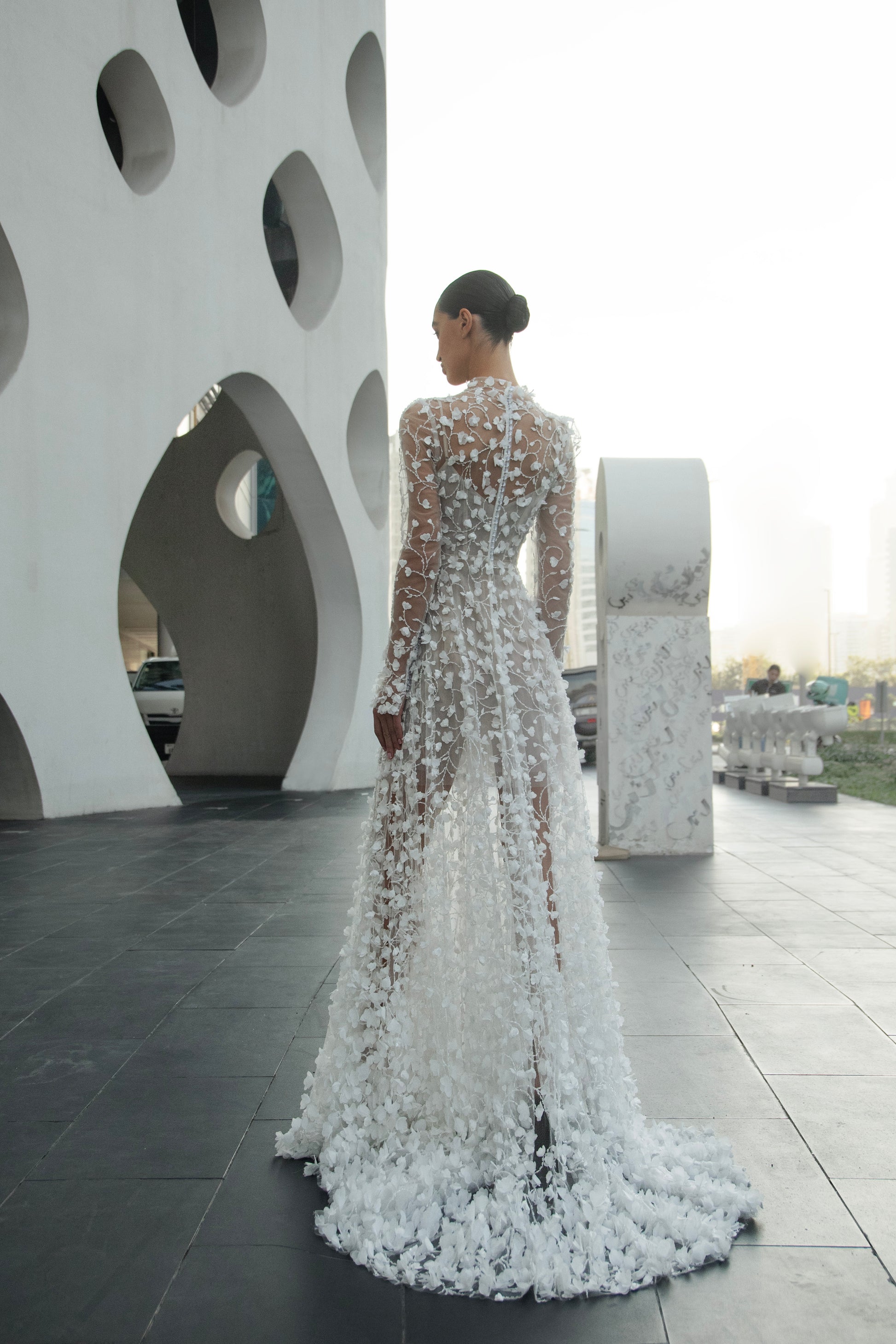 Modern 3D floral bridal mini gown with sheer long sleeves and detachable tulle overskirt.