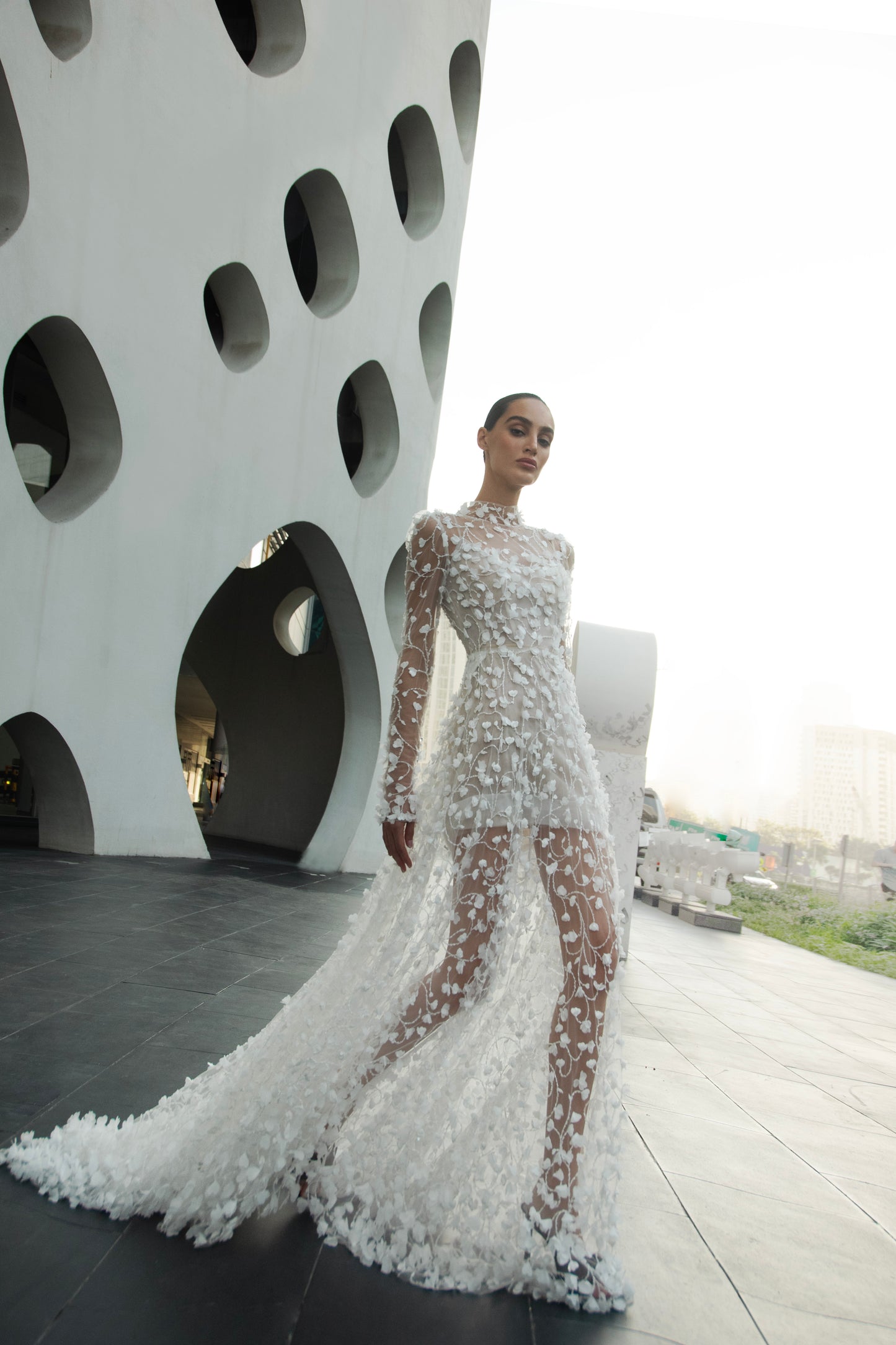 Modern 3D floral bridal mini gown with sheer long sleeves and detachable tulle overskirt.