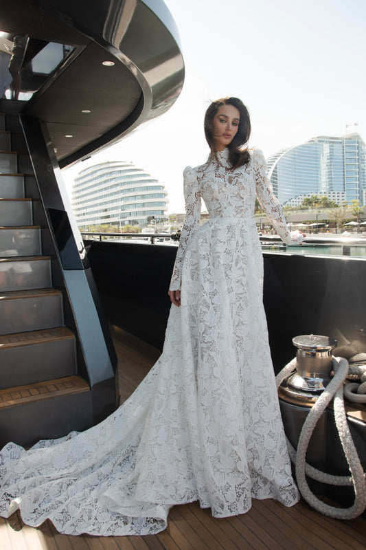 High-neck lace wedding gown with long puff sleeves, open back, and chapel-length train.