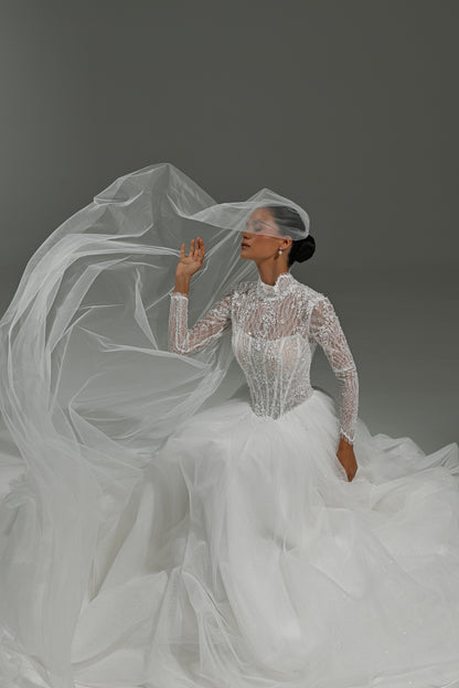 Lace high-neck wedding dress with corset bodice – model seated in the voluminous tulle skirt with the veil flowing