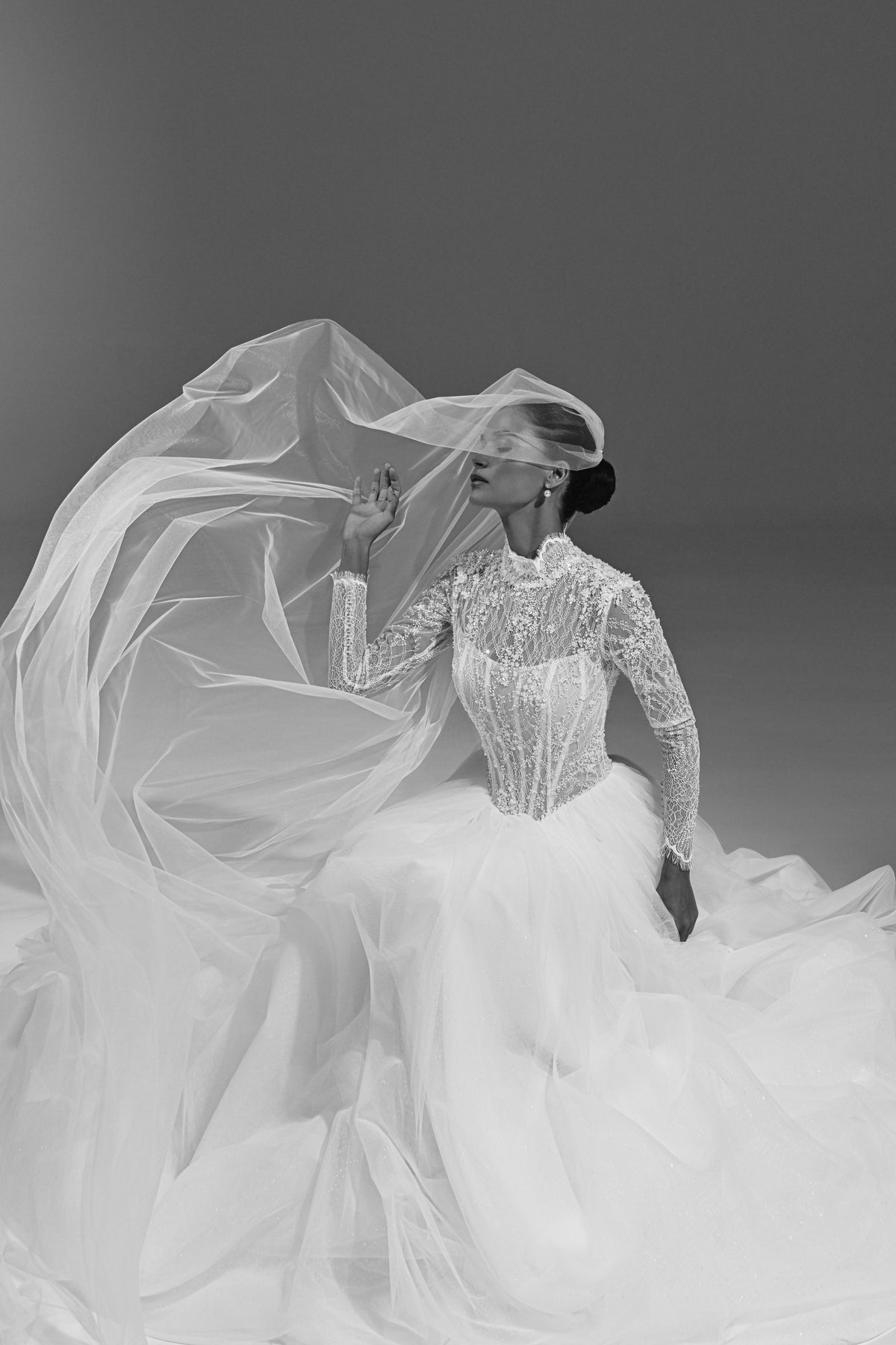 Lace high-neck wedding dress – seated pose with the tulle skirt and veil spread around