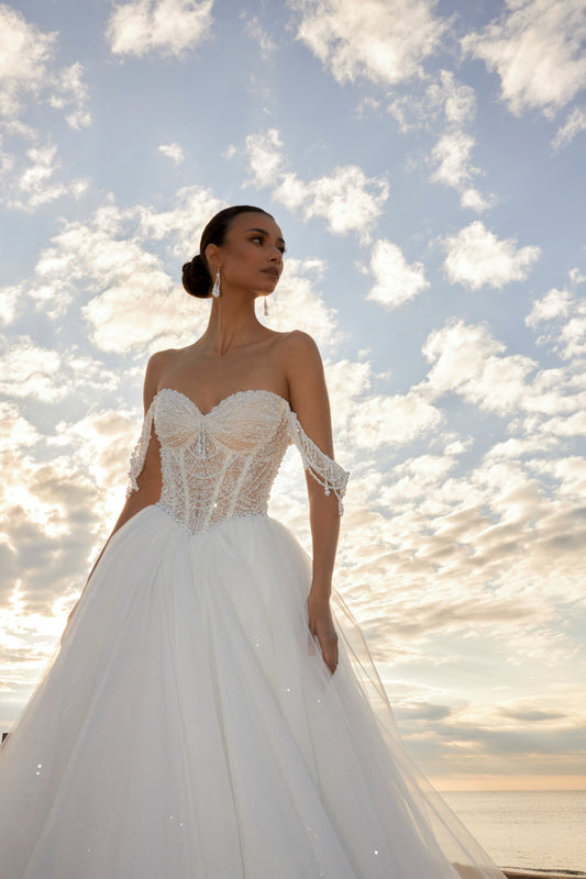 Sleeveless A-line wedding dress with pearl bodice, sweetheart neckline, glitter tulle skirt, off-the-shoulder pearl straps, and chapel train.