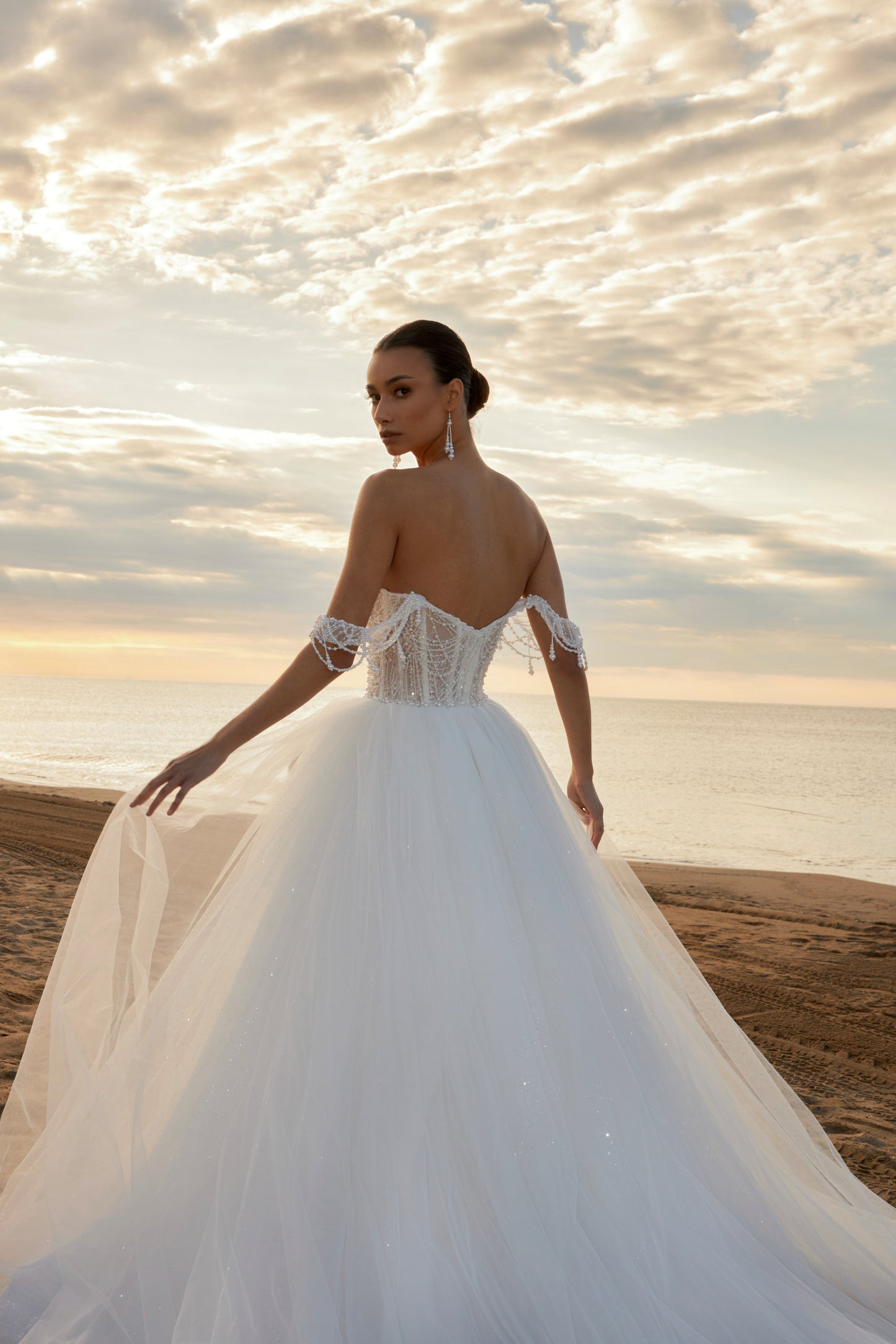 Sleeveless A-line wedding dress with pearl bodice, sweetheart neckline, glitter tulle skirt, off-the-shoulder pearl straps, and chapel train.