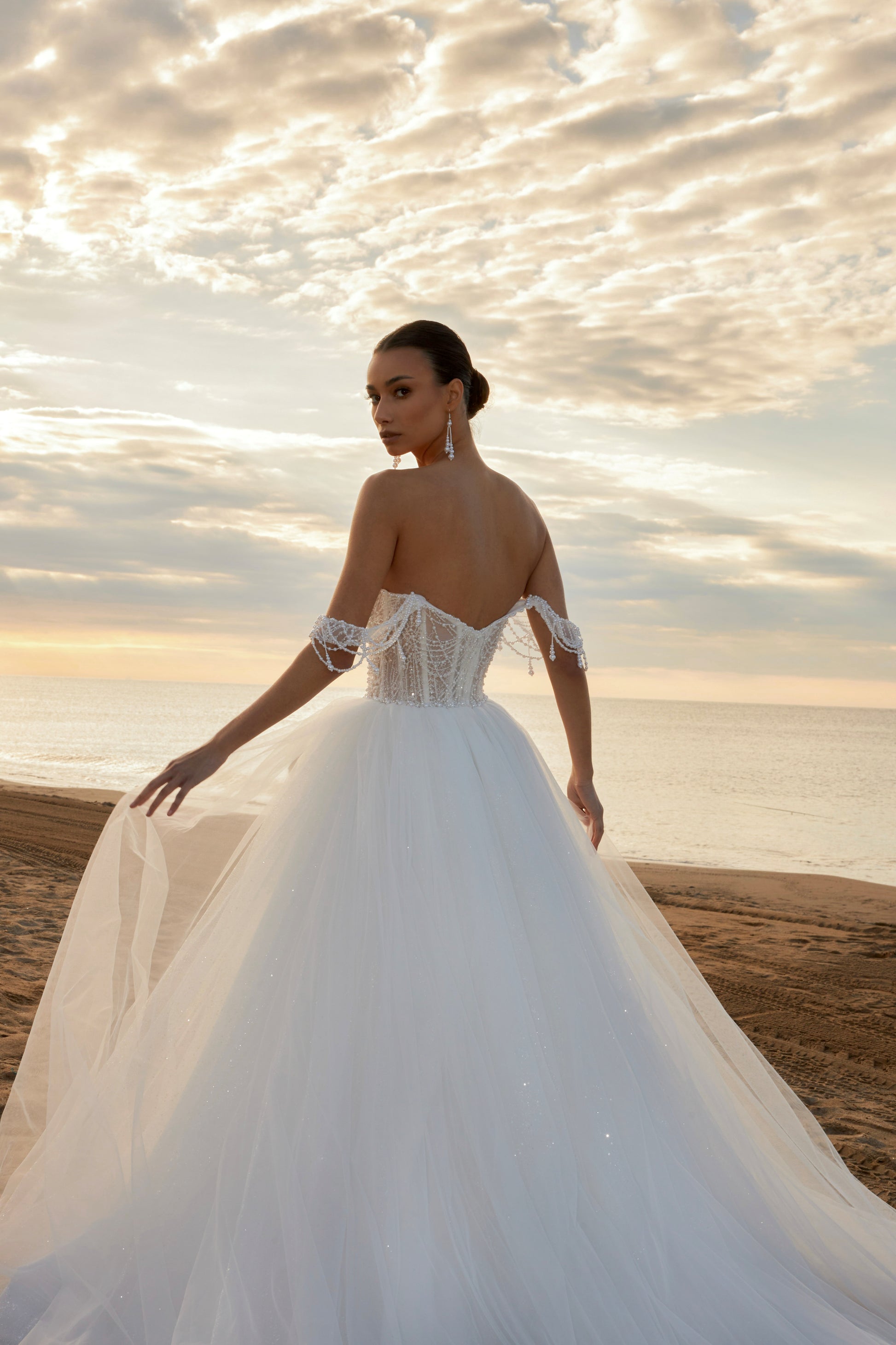 Sleeveless A-line wedding dress with pearl bodice, sweetheart neckline, glitter tulle skirt, off-the-shoulder pearl straps, and chapel train.