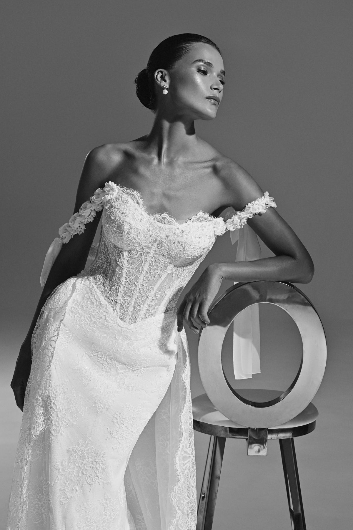Lace wedding dress with off-shoulder corset – black and white view leaning on a chair