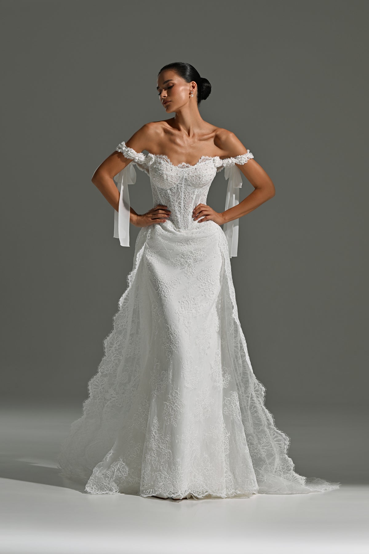 Lace wedding dress with detachable scalloped overskirt train – standing front view with ribbon bows at the shoulders