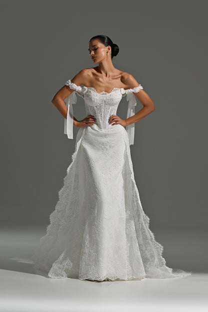 Lace wedding dress with detachable scalloped overskirt train – standing front view with ribbon bows at the shoulders