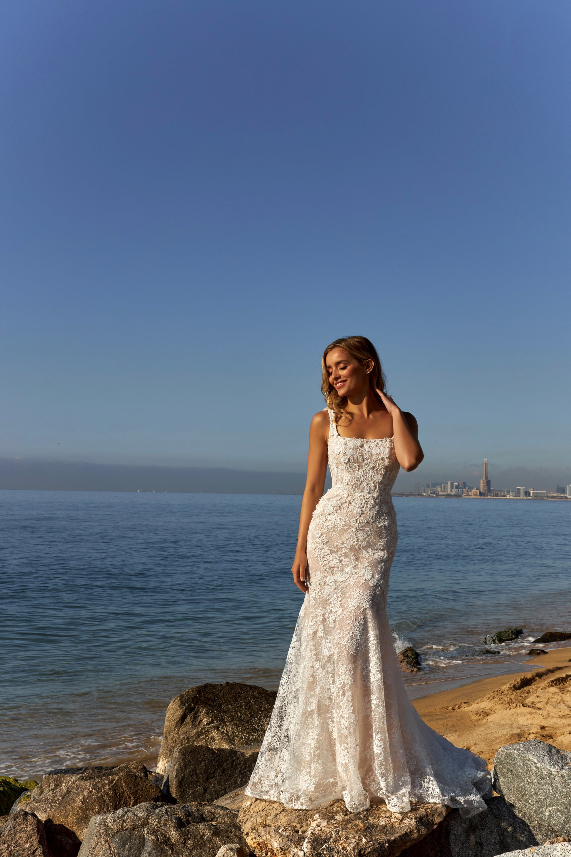 Mermaid trumpet lace bridal gown with square neckline, wide straps, open square back, zip closure, and fishtail train.