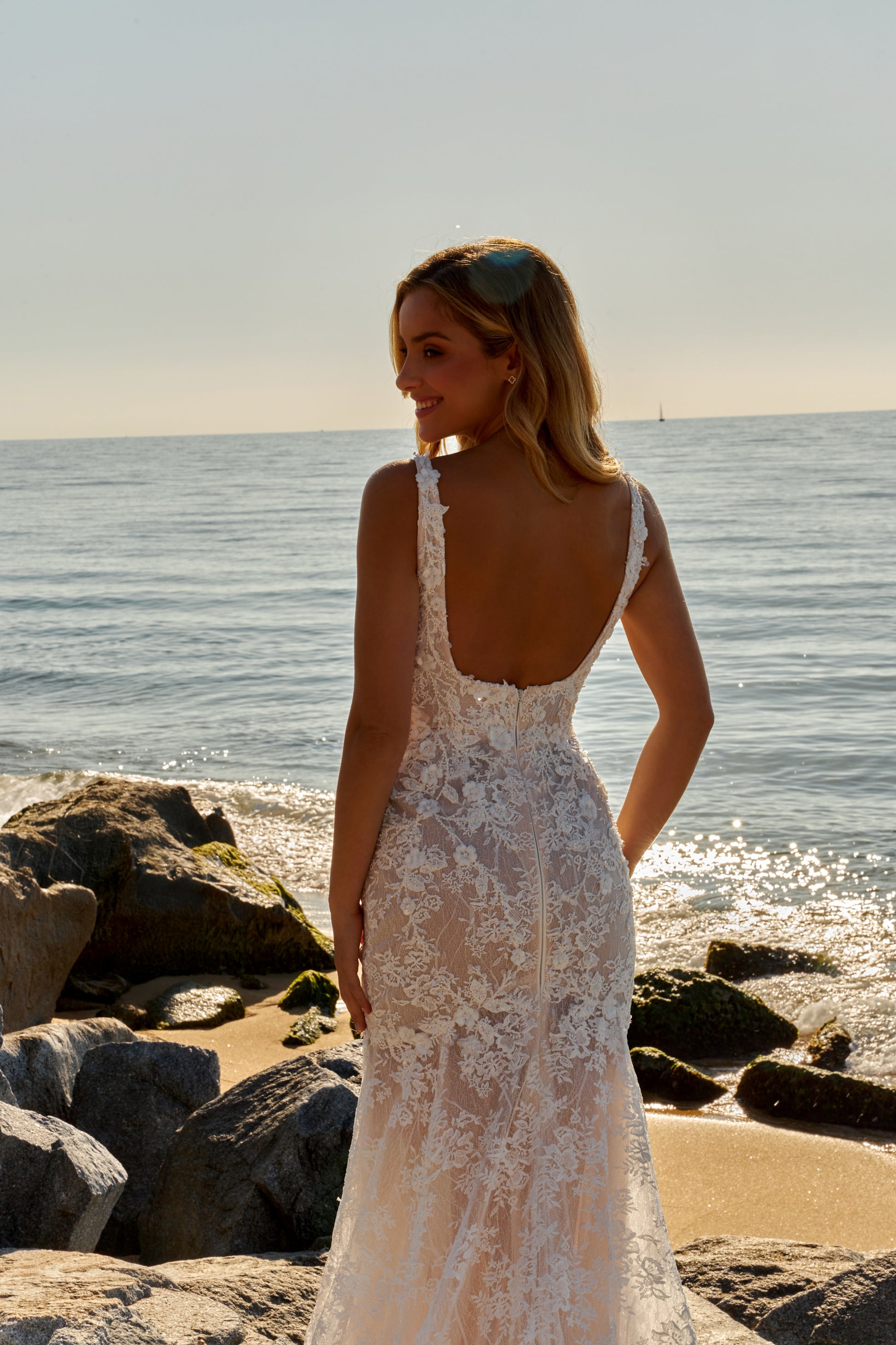 Mermaid trumpet lace bridal gown with square neckline, wide straps, open square back, zip closure, and fishtail train.