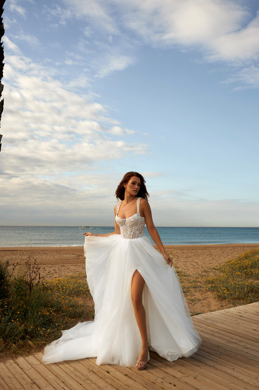 Sleeveless A-line bridal gown with boat neckline, lace bodice, wide straps, square back, glitter tulle slit skirt, and chapel train.