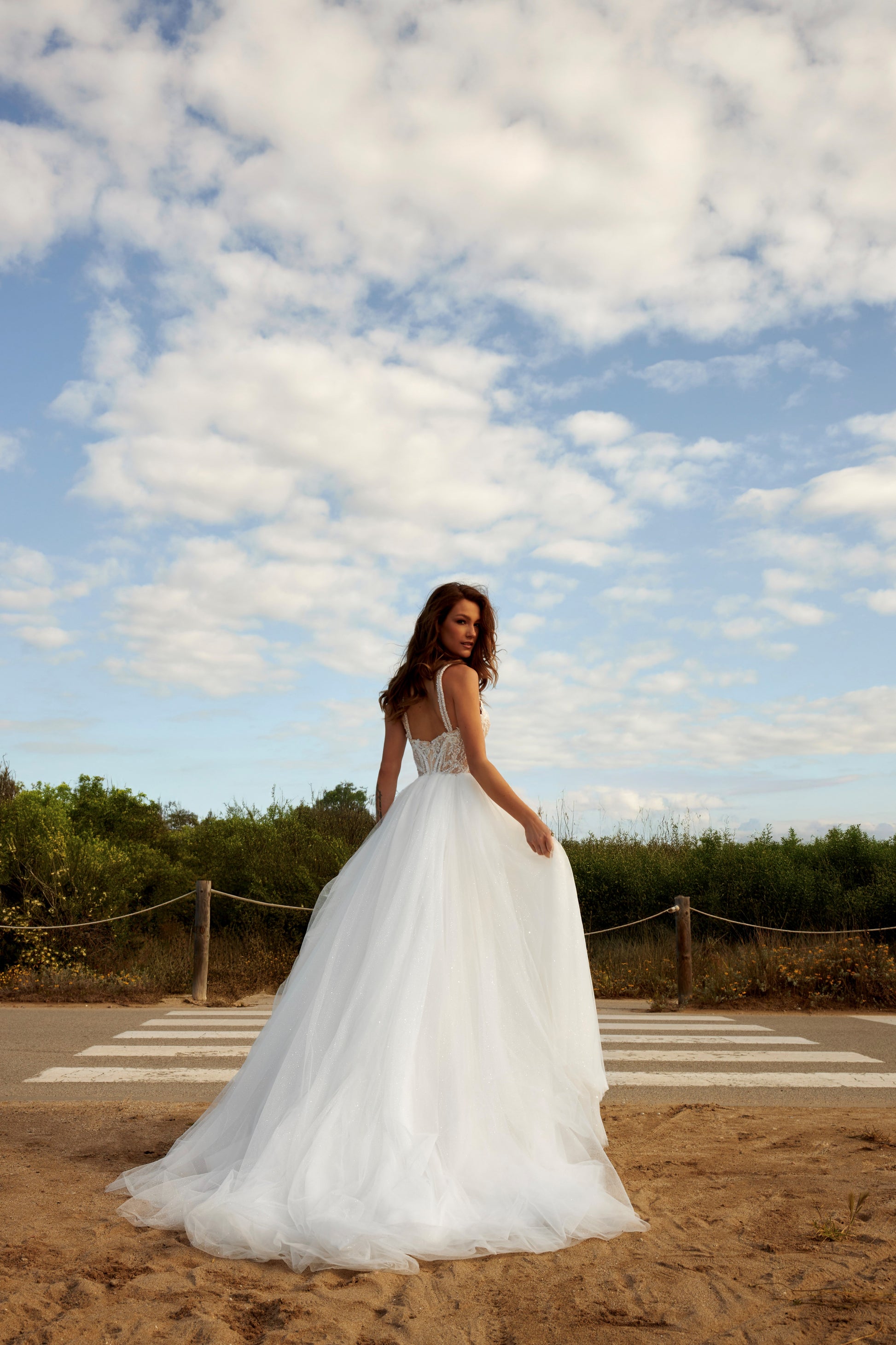 Sleeveless A-line bridal gown with boat neckline, lace bodice, wide straps, square back, glitter tulle slit skirt, and chapel train.