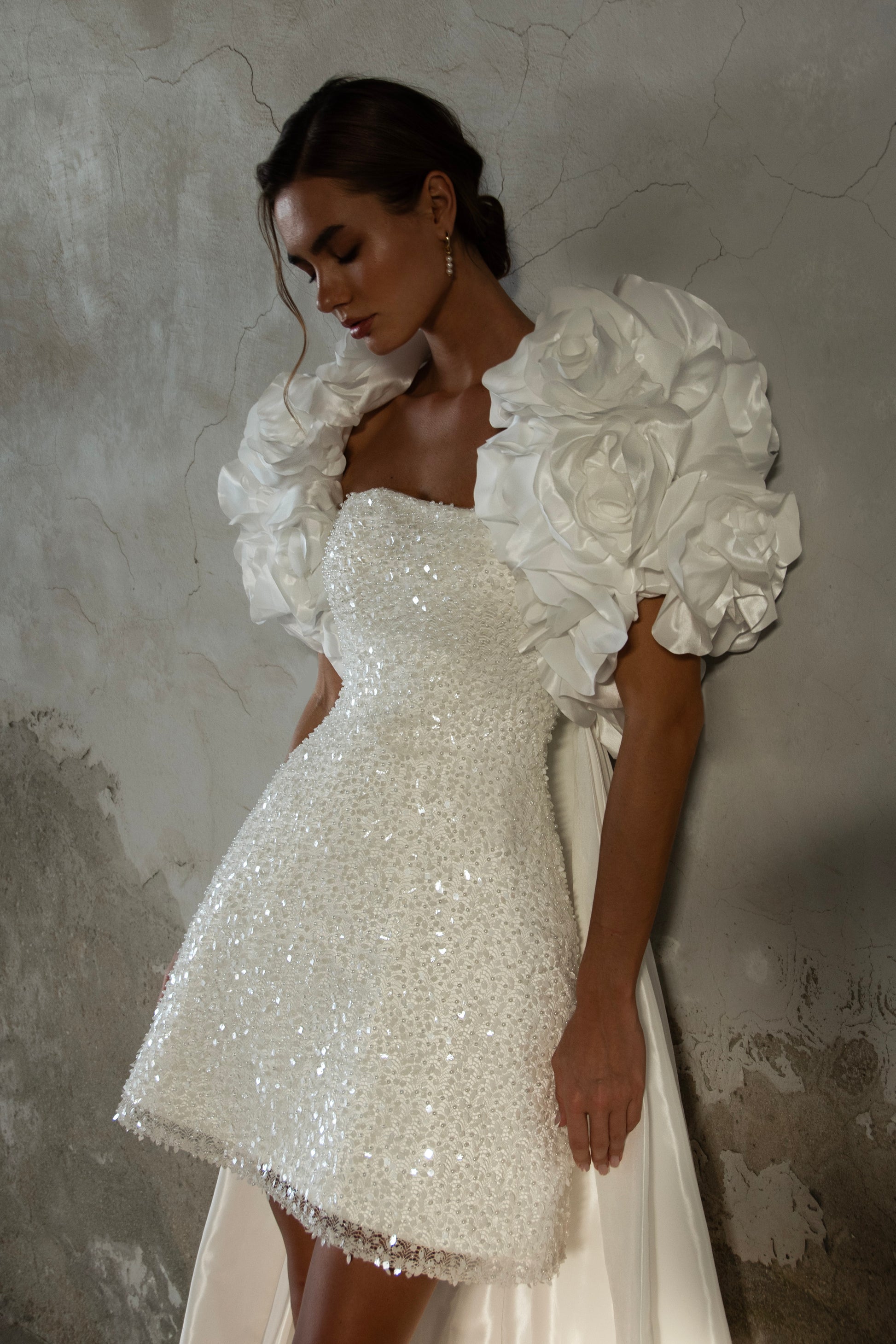 Bride wearing short beaded mini wedding dress with voluminous floral bolero and detachable satin train, photographed at sunset airfield.