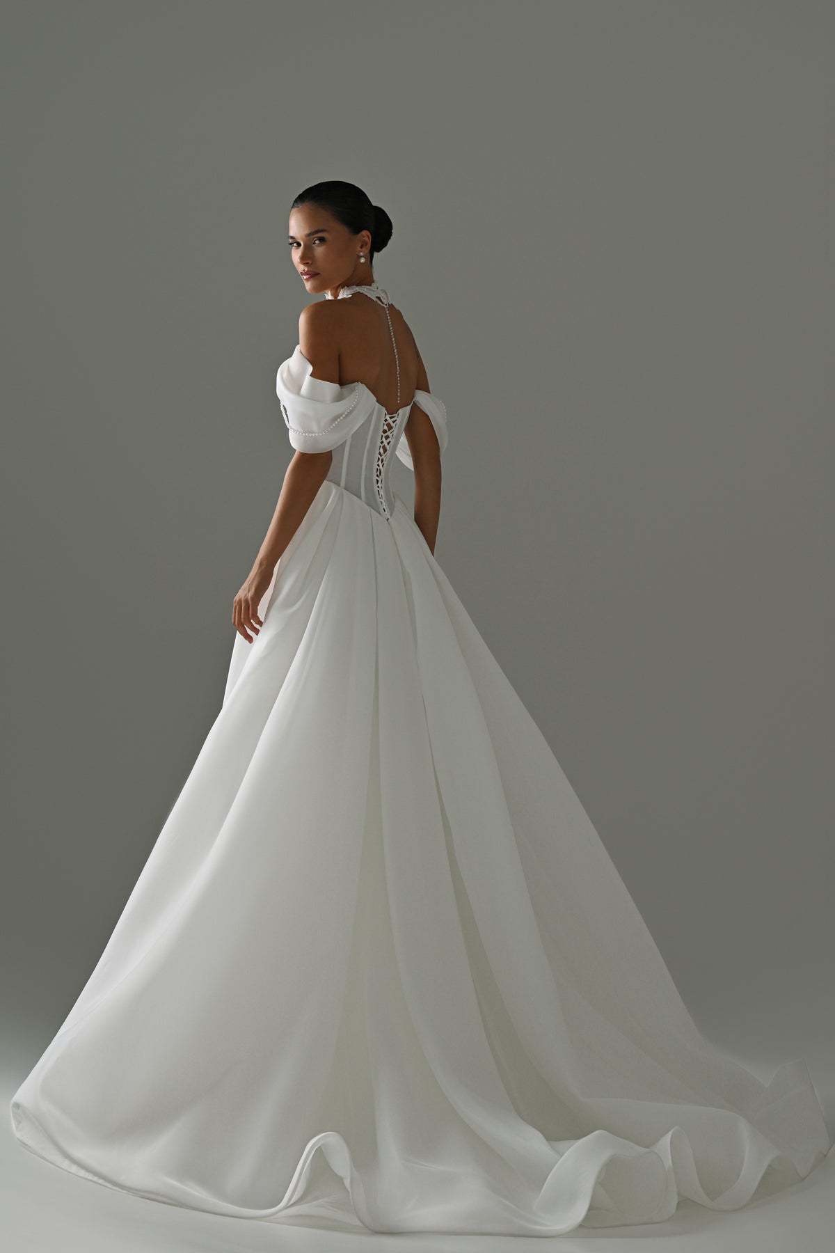 Off-shoulder organza A-line wedding dress with puff sleeves and lace corset – back three-quarter view of the full skirt