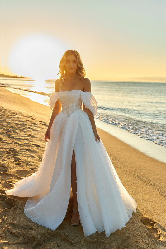 Princess A-line organza bridal gown with short off-the-shoulder draped sleeves, pearl details, slit skirt, drop-down waist, and chapel train.