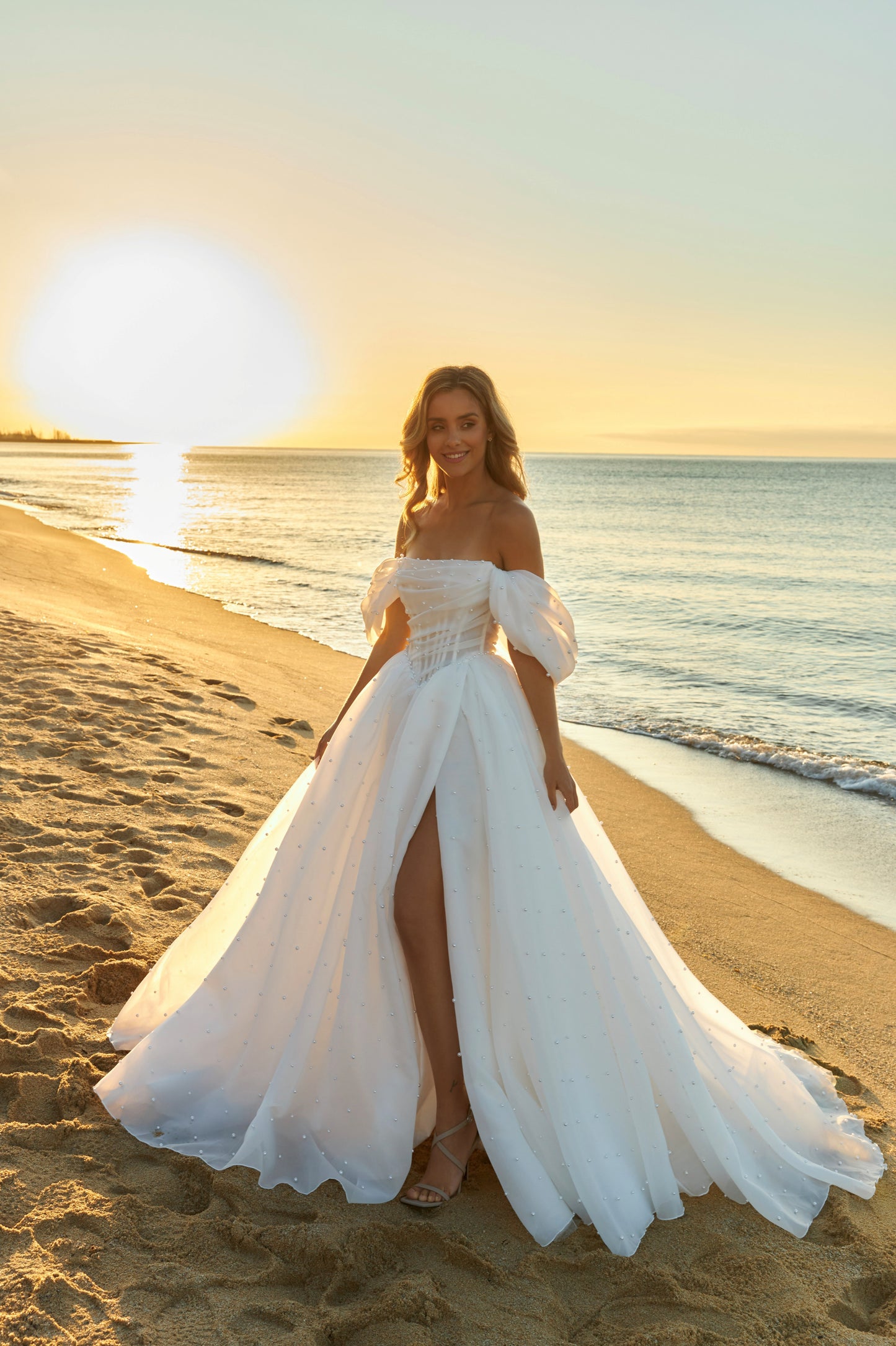 Princess A-line organza bridal gown with short off-the-shoulder draped sleeves, pearl details, slit skirt, drop-down waist, and chapel train.