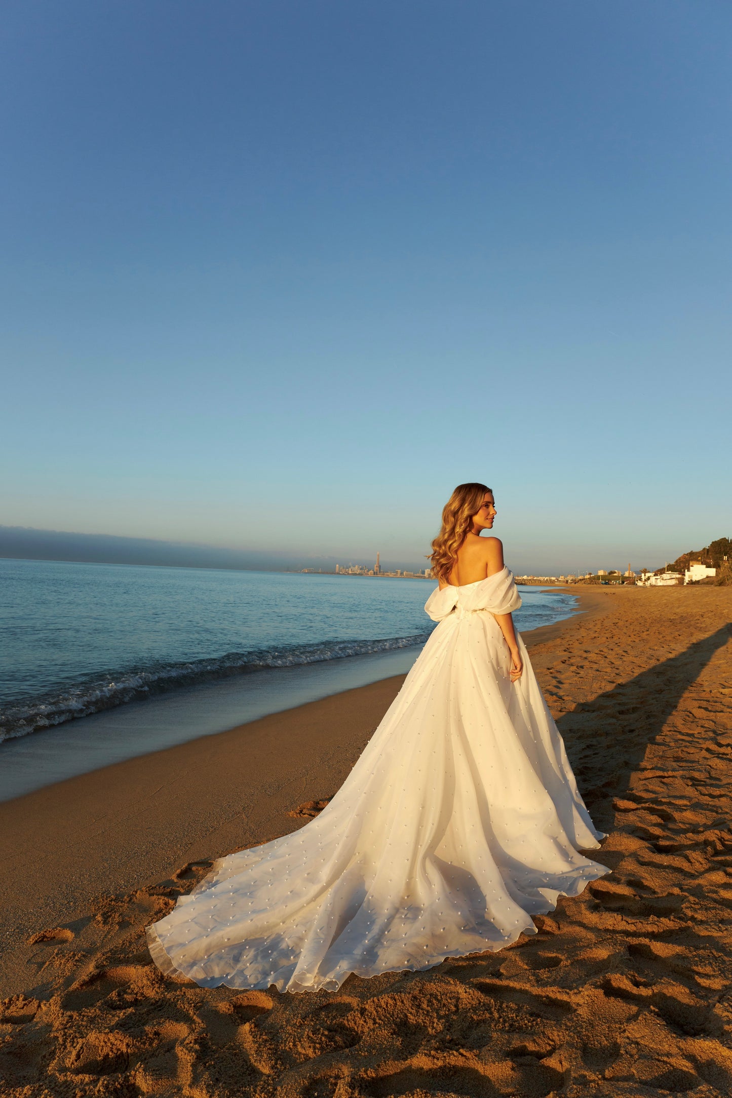 Princess A-line organza bridal gown with short off-the-shoulder draped sleeves, pearl details, slit skirt, drop-down waist, and chapel train.
