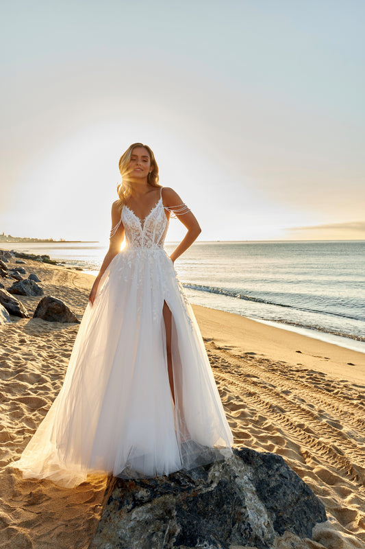 Sleeveless A-line lace bridal gown with spaghetti straps, deep-V neckline, open V-back, slit tulle skirt, and chapel train.