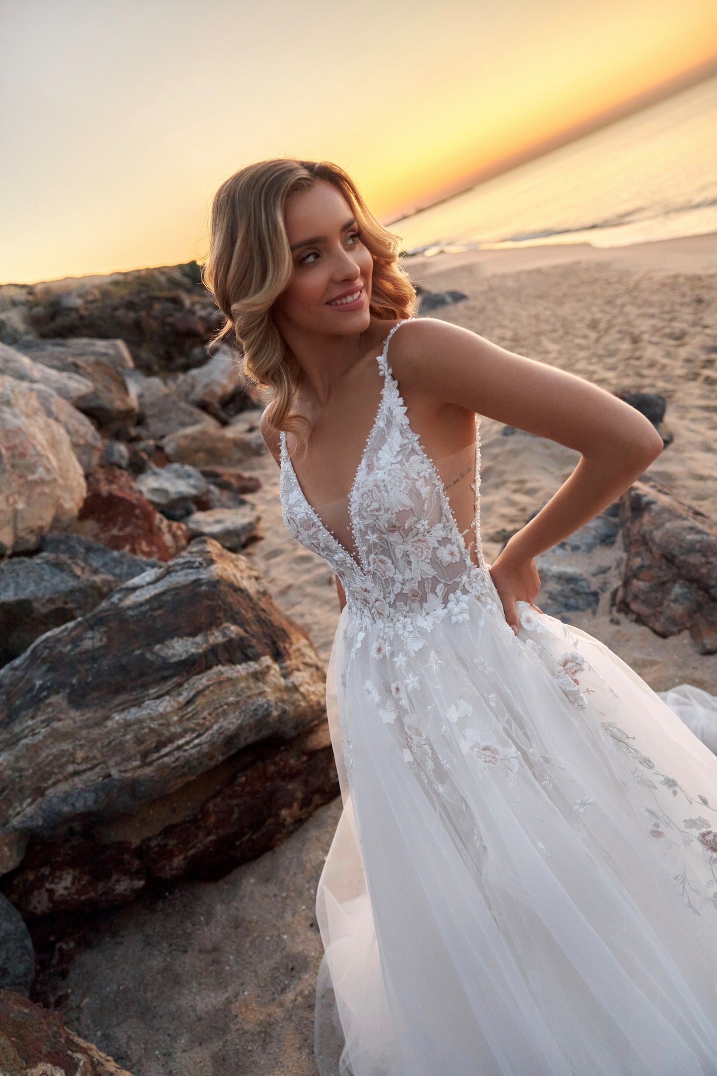 Sleeveless lace A-line bridal gown with spaghetti straps, deep-V neckline, backless zip closure, lace tulle skirt, and chapel train.