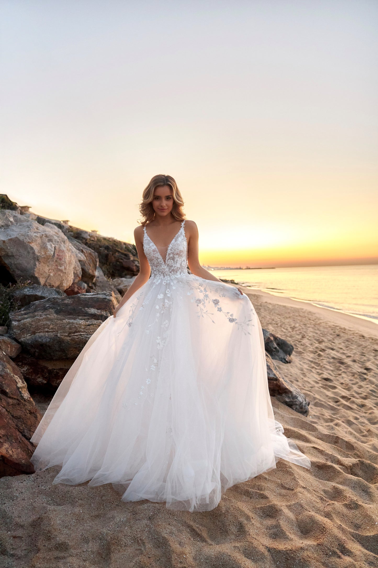 Sleeveless lace A-line bridal gown with spaghetti straps, deep-V neckline, backless zip closure, lace tulle skirt, and chapel train.