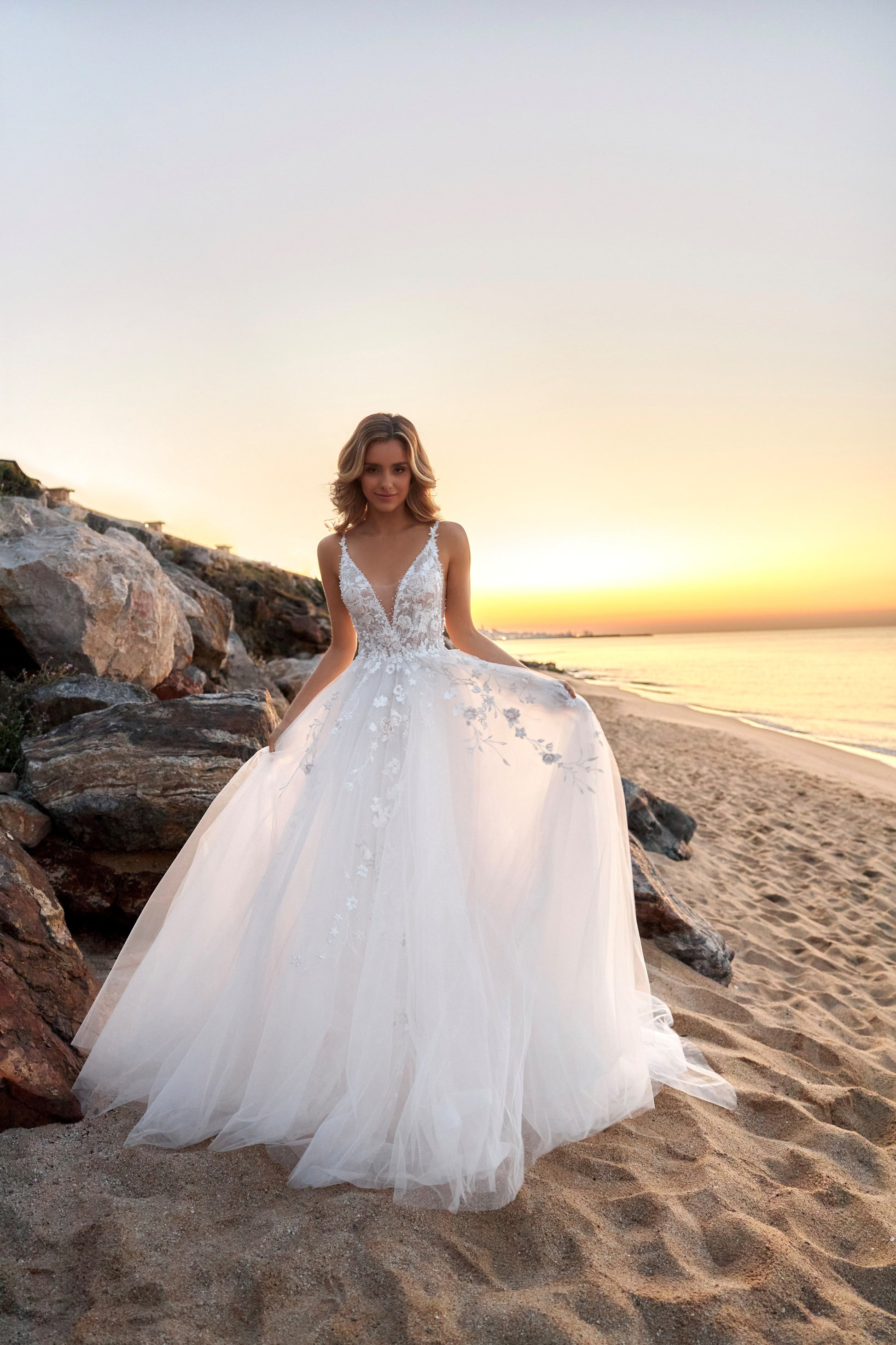 Sleeveless lace A-line bridal gown with spaghetti straps, deep-V neckline, backless zip closure, lace tulle skirt, and chapel train.